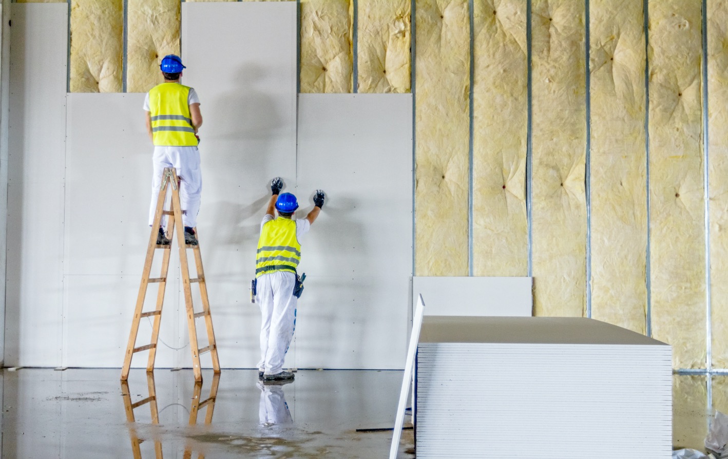 tradesmen installing boards on top of a wall filled with rockwool insulation